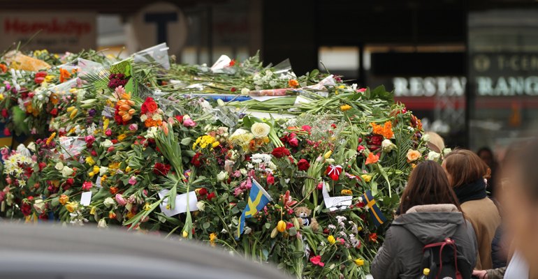 One of several police vehicles parked outside of Åhlens buried under flowers as passersby express grief over the attack but also gratitude and appreciation towards police and emergency services.