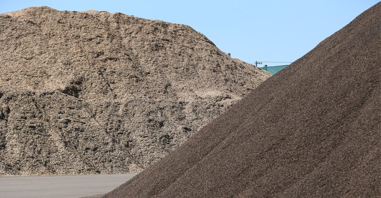 Stockpiles of imported biomass fuels, woodchips (left) and palm kernel shells (PKS) at a Japanese port terminal.