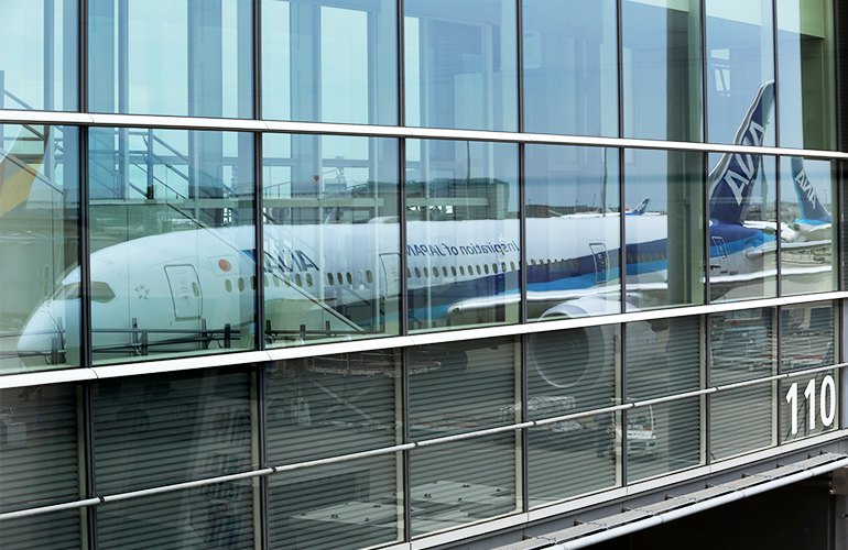 A reflection of an ANA aircraft parked by a gate.
